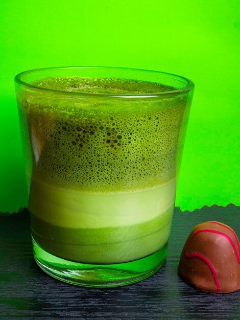 Chá verde quente com leite com matcha em pó no espaço livre de fundo verde para texto
