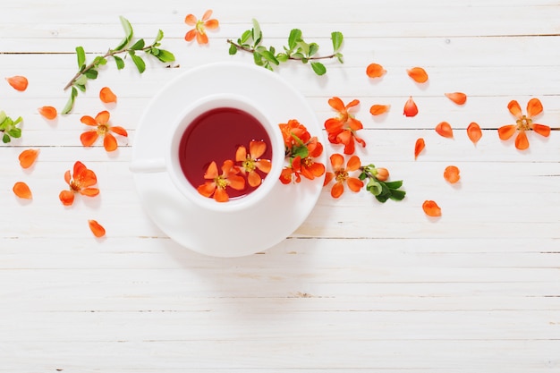 Chá vermelho com flores no espaço em branco de madeira