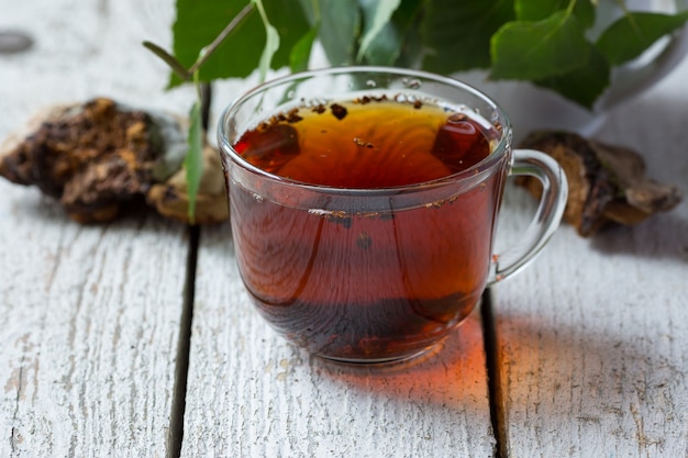 Foto chaga en un vaso sobre una superficie de madera clara. bebida de setas de abedul. fitoterapia. superalimento orgánico. copia espacio