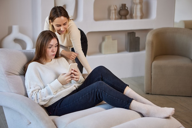 Chaiselongue mit zwei Schwestern mit Telefon auf dem Sofa