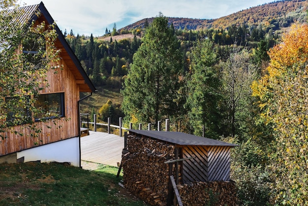 Chalé de Montaña. Casa, cabaña en las montañas. Leña bajo un dosel.