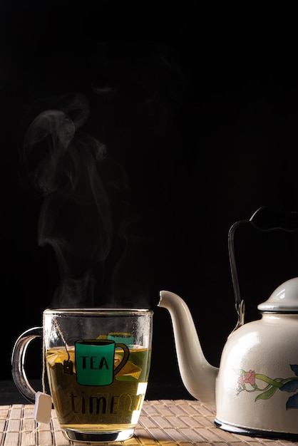 Chaleira e xícara de chá, ambas saindo da fumaça em uma esteira de madeira