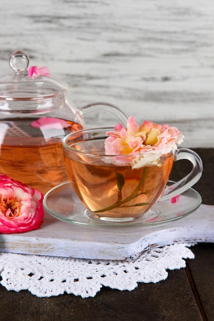 Foto chaleira e xícara de chá de rosa de chá a bordo em guardanapo na mesa de madeira sobre fundo de madeira