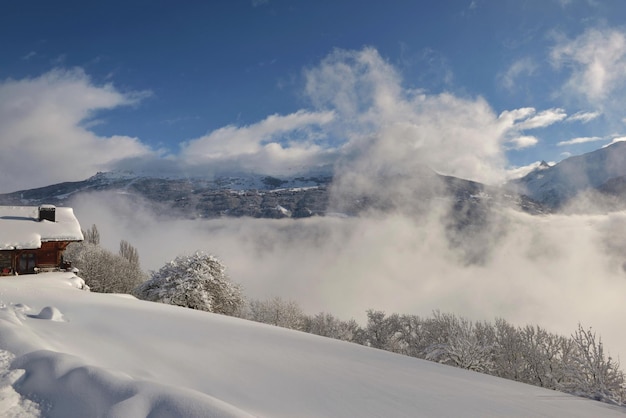 Chalet mit Blick auf bewölktes Tal im schneebedeckten Berg