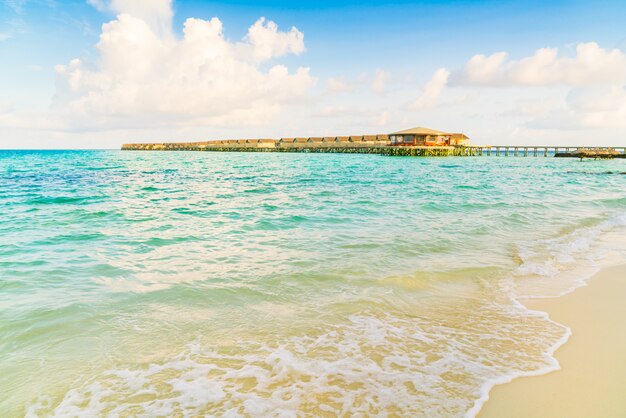 Chalets hermosos del agua en la isla tropical de maldivas en el tiempo de la salida del sol.