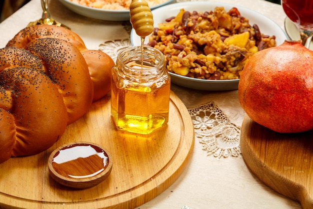 Challah auf einem Holzbrett am Feiertag von Rosch Haschana in der Nähe von Honigäpfeln und Menorah