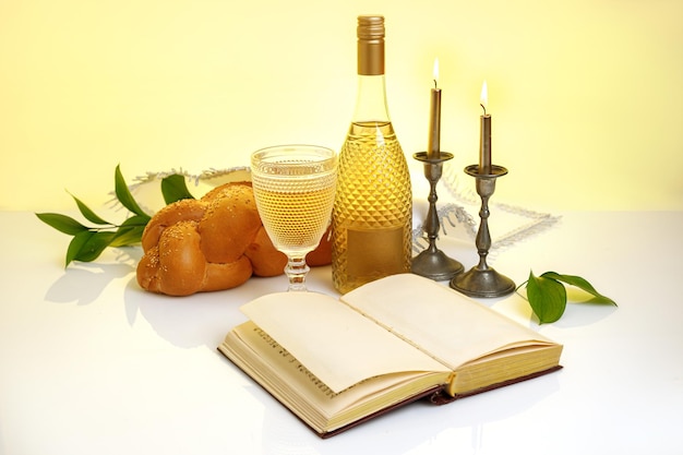 Challah-Brot bedeckt mit einer speziellen Serviette Schabbat-Wein-Torah und Kerzen auf weißem Hintergrund Traditionelles jüdisches Schabbat-Ritual Schabbat Shalom
