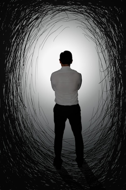 Foto challenge-konzeptbild hintergrundansicht eines geschäftsmannes mit hellem licht am ende eines dunklen tunnels