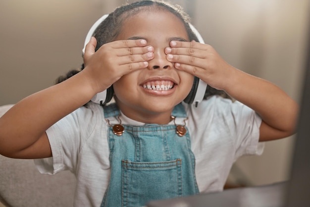 Chamada de vídeo de menina e criança brincando de esconde-esconde em casa sorrindo e se divertindo Fones de ouvido de rosto e criança em webinar conferência on-line ou bate-papo por vídeo em casa brincando de esconde-esconde aproveitando o tempo no laptop