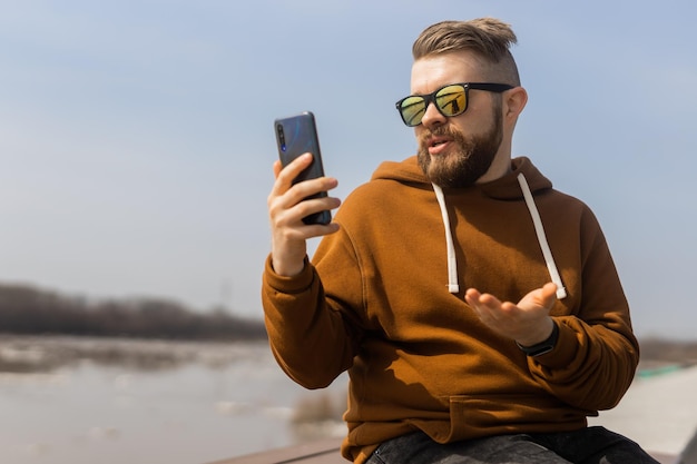 Chamada de vídeo do homem de comunicação de mídia social usando a mola do telefone inteligente móvel ao ar livre copie o espaço para