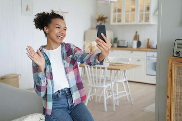 Chamada de vídeo por telefone Uma jovem afro-americana feliz está falando com um amigo no smartphone