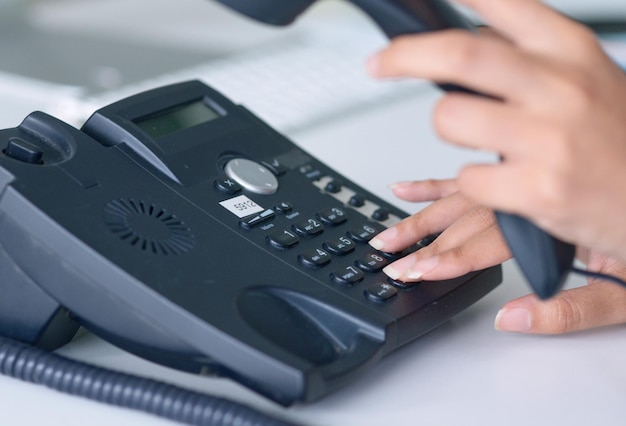 Chamada telefônica e close-up nas mãos da recepcionista para comunicação de conversa de trabalho ou telemarketing Telefone manual e secretária do escritório ligando para crm ou administração para entrar em contato conosco em um telefone fixo