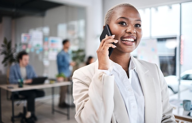 Chamada telefônica excitada e mulher negra no escritório para comunicação conversa ou bate-papo Smartphone feliz e profissional de negócios ouvindo conversando ou discutindo com contato no local de trabalho de coworking