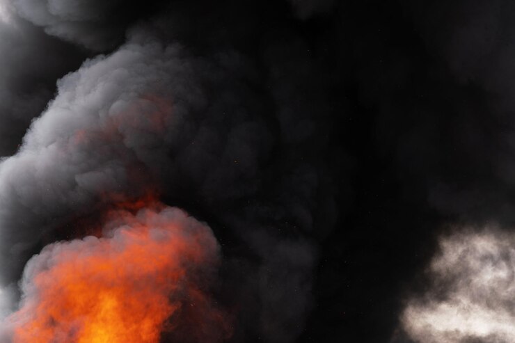 Chamas perigosas de fogo vermelho forte e nuvens de movimento de fumaça preta cobriam o céu. Desfocagem, borrão de movimento do fogo e alta temperatura das chamas. Dispersão atmosférica e de fumaça.