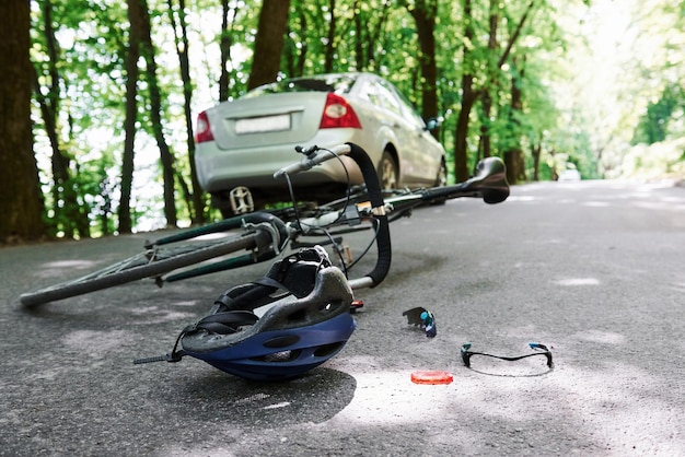 Chame uma emergência acidente de bicicleta e carro de cor prateada na estrada na floresta durante o dia