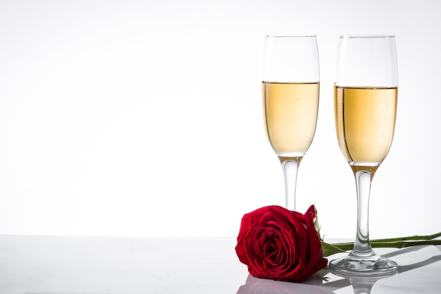Champagne-Cup und Rotrose auf weißer Oberfläche