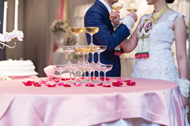 Champagne-Gläser in der Hochzeitszeremonie mit Braut- und Bräutigamhintergrund