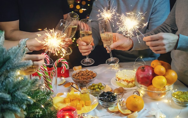 Champagner in der Hand vor dem Hintergrund des Weihnachtsbaumes. Menschen.