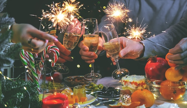 Champagner in der Hand vor dem Hintergrund des Weihnachtsbaums. Personen. Selektiver Fokus. Urlaub.