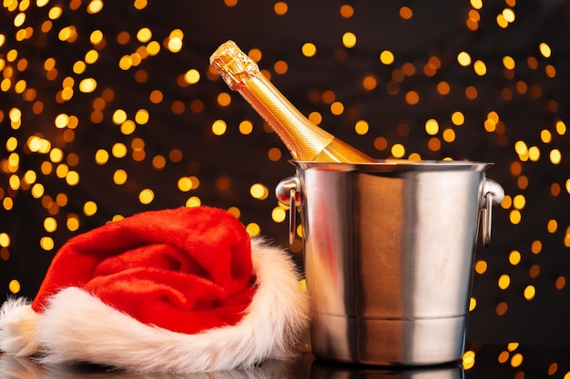 Champagner- und Weihnachtsmannhut auf verschwommener Girlande