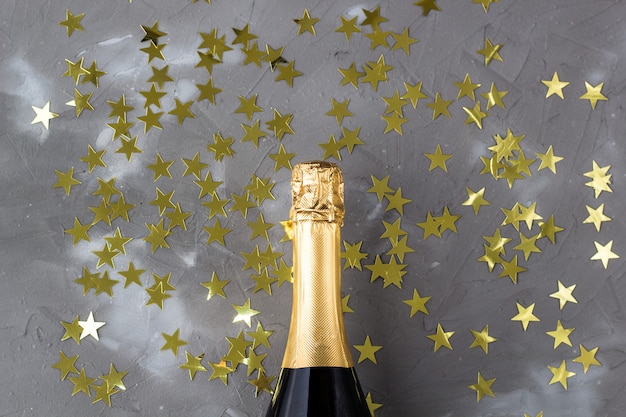 Champagnerflasche mit goldenen Konfettisternen. Konzept für Weihnachten, Neujahr, Geburtstag oder Hochzeit