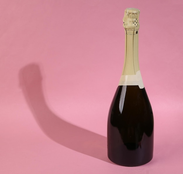 Foto champagnerflasche mit langem schatten auf rosa hintergrund