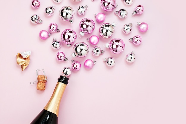 Champagnerflasche mit rosa und silbernen Weihnachtskugeln. Flache Lage, trendiges Urlaubskonzept von oben.