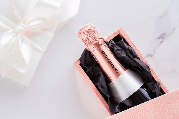 Champagnerflasche und Geschenkbox auf Marmor Silvester, Weihnachten, Valentinstag oder Hochzeitsgeschenk und Luxusproduktverpackung für Getränkemarke