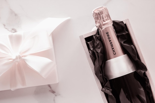 Champagnerflasche und Geschenkbox auf Marmor Silvester, Weihnachten, Valentinstag oder Hochzeitsgeschenk und Luxusproduktverpackung für Getränkemarke