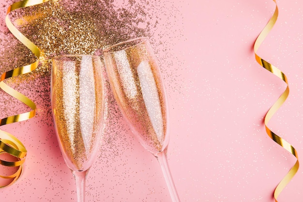 Champagnerflöten mit Glitzer auf rosa Tisch