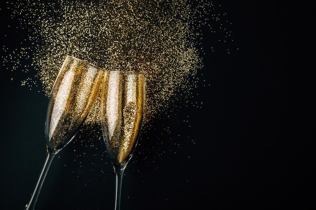 Foto champagnerflöten und glitzer vor schwarzem hintergrund