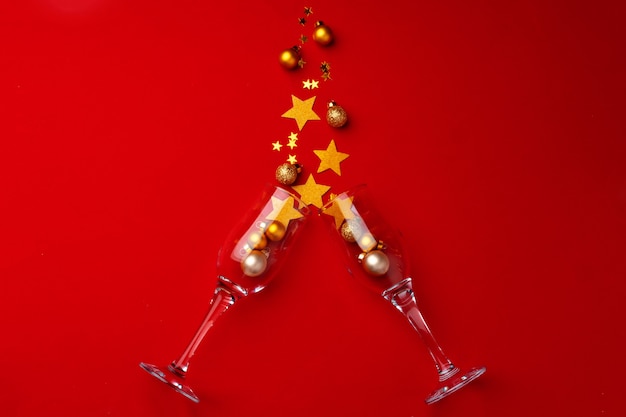 Champagnerglas mit Glitzerkonfetti auf rotem Hintergrund flache Draufsicht