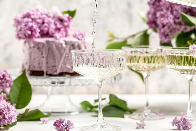 Champagnerwein und Blaubeertörtchen mit Blumenstrauß aus lila blühenden Fliedern Postkartenhintergrund Französische Küche