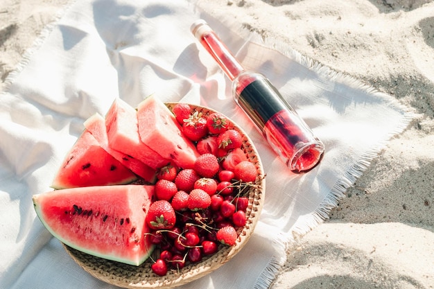 Champán con una bandeja de frutas, fresas y cerezas en un picnic