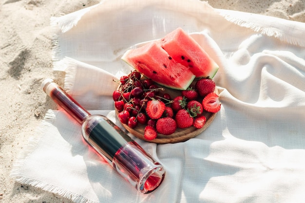 Champán con una bandeja de frutas, fresas y cerezas en un picnic