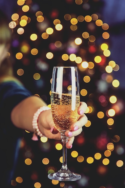 Foto champán en mano contra el árbol de navidad