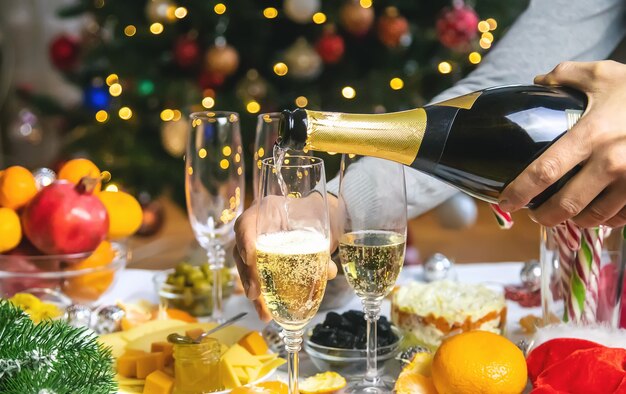 Champán en mano con el telón de fondo del árbol de Navidad. Gente. Enfoque selectivo. Fiesta.