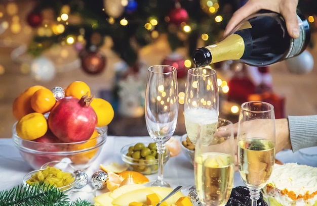 Champán en mano con el telón de fondo del árbol de Navidad. Gente. Enfoque selectivo. Fiesta.