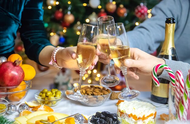 Champán en mano con el telón de fondo del árbol de Navidad. Personas.