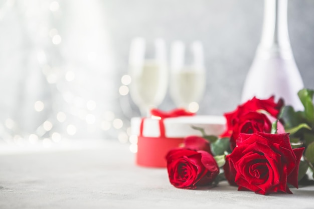 Champán y rosas rojas con bokeh. Entorno de San Valentín con rosas rojas y presente.