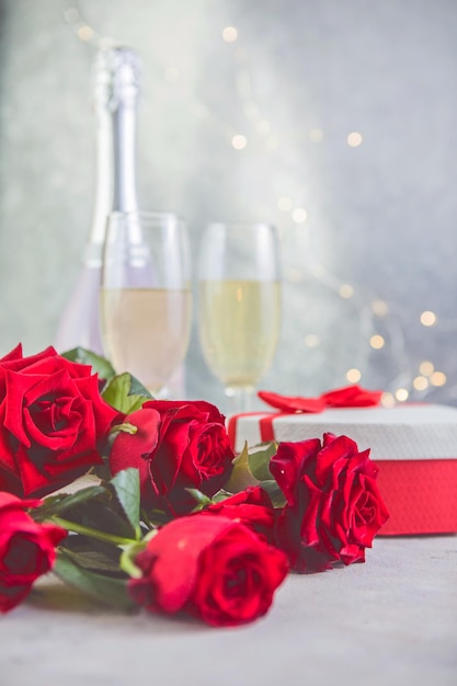 Champán y rosas rojas con bokeh. Entorno de San Valentín con rosas rojas y presente.