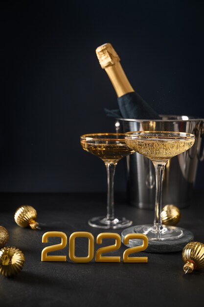 Champanhe de ano novo em taças de vinho e garrafa em balde decorado enfeites de ouro de Natal