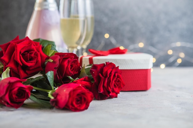 Champanhe e rosas vermelhas com bokeh. Cenário do dia dos namorados com rosas vermelhas e presente