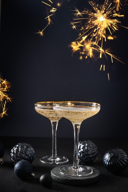 Champanhe festivo em taças de vinho e enfeites de Natal azul na festa de ano novo com fundo escuro