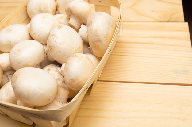 Champignon de cogumelos frescos em uma cesta em um fundo de madeira