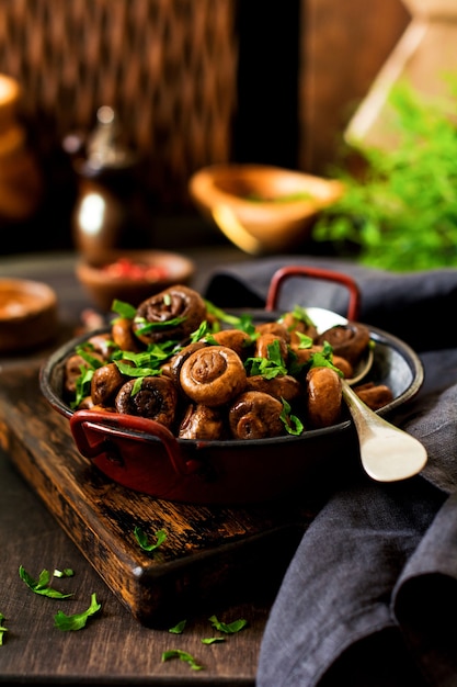 Champignon de cogumelos frito em molho de soja, com pimenta e cebola cozida no vapor em uma velha tigela de metal sobre uma velha mesa vintage. foco seletivo