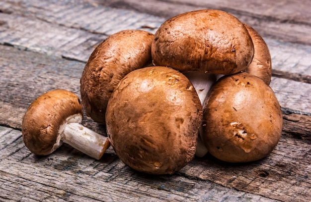 Champignon de cogumelos marrons frescos em uma velha mesa de madeira