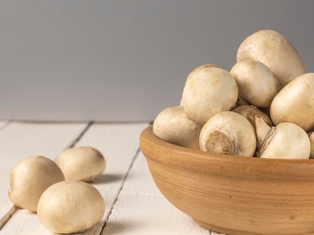 Champignon em um prato em um close-up de fundo branco de madeira com uma cópia do espaço.