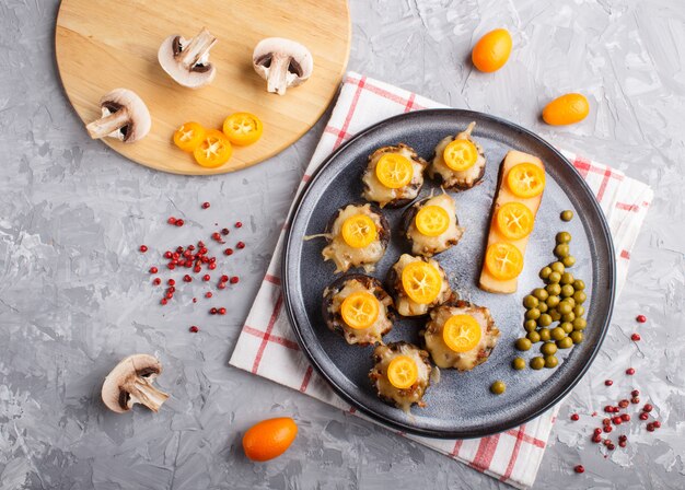 Champignon frito recheado com kumquats de queijo e ervilhas verdes sobre um fundo cinza de concreto close-up