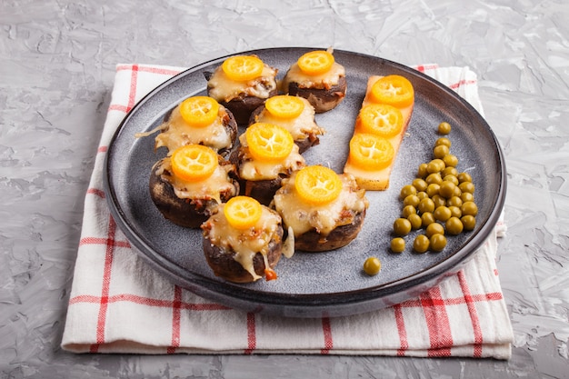 Champignon frito recheado com queijo, kumquats e ervilhas verdes sobre um fundo cinza de concreto